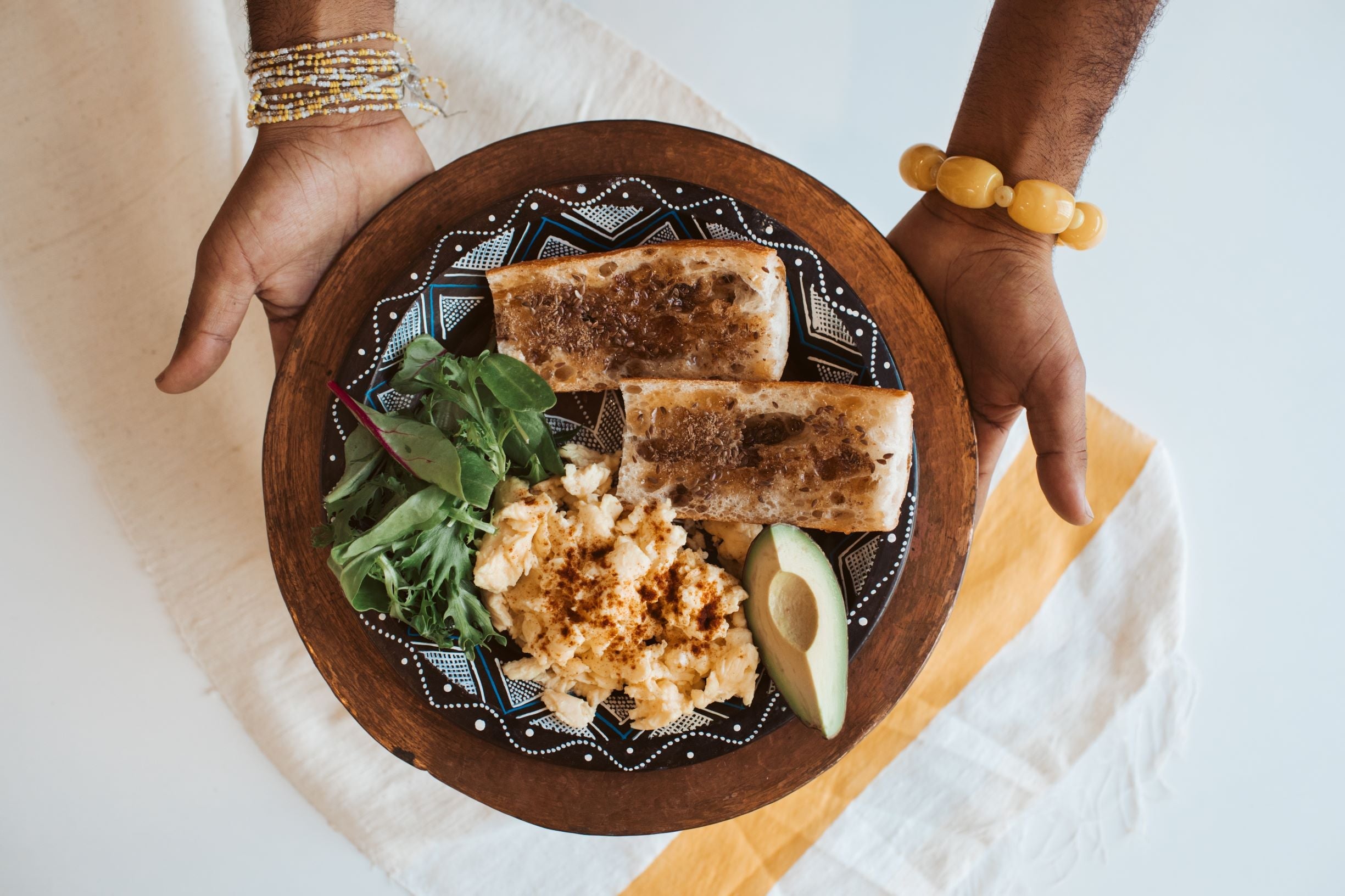 Plate with Niter Kibbeh and Berbere Scrambled Eggs, Telba on toast, and greens