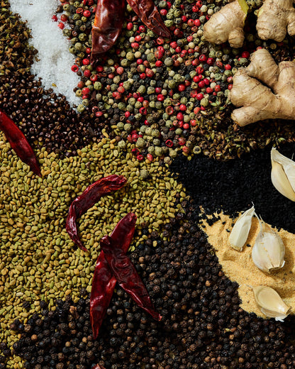 Flat lay of Ethiopian spices including black seeds, fenugreek, garlic, black pepper, ginger, and whole dried chilies.