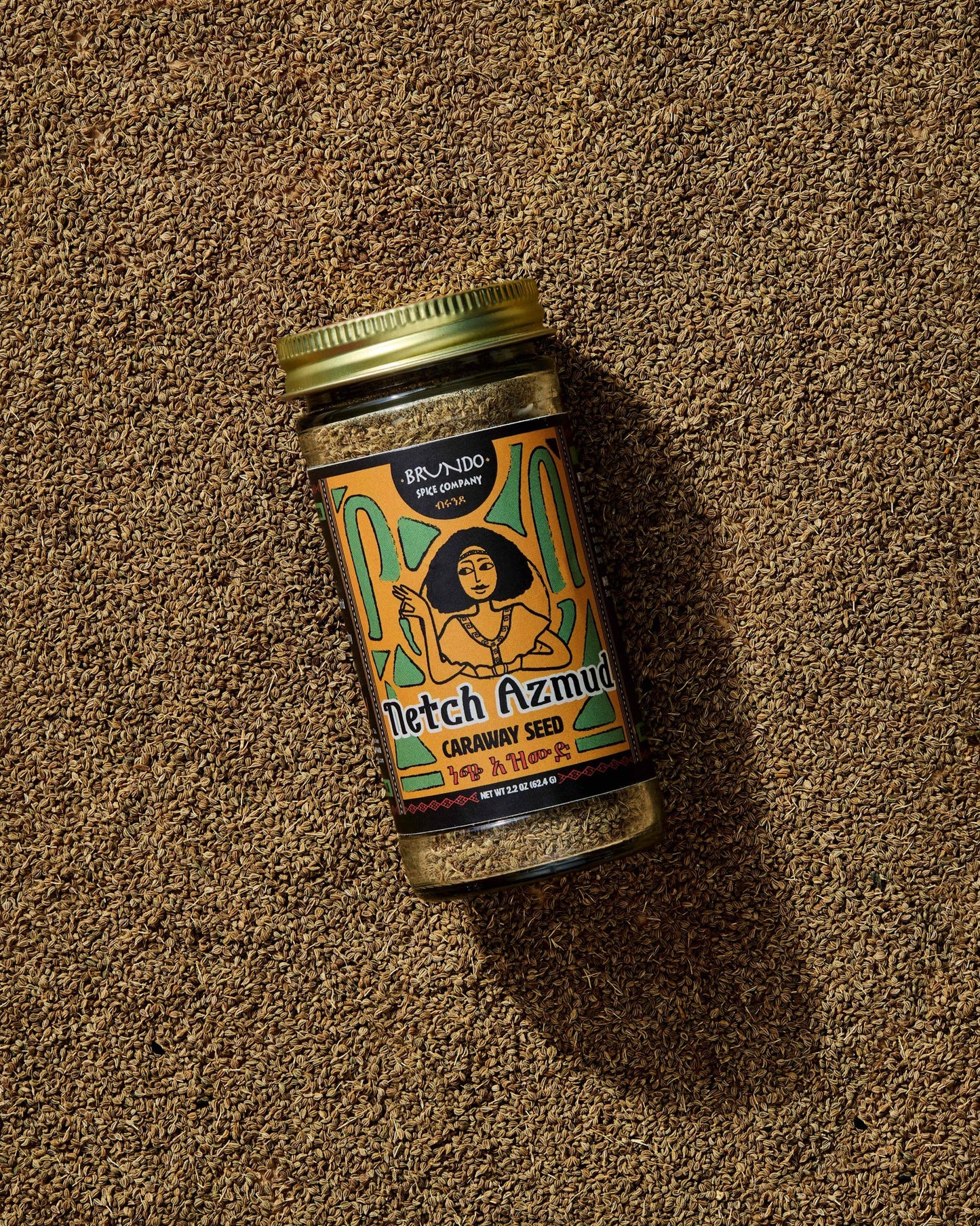 Brundo Spice Company Netch Azmud Ethiopian Caraway Seed jar resting on a bed of whole caraway seeds.