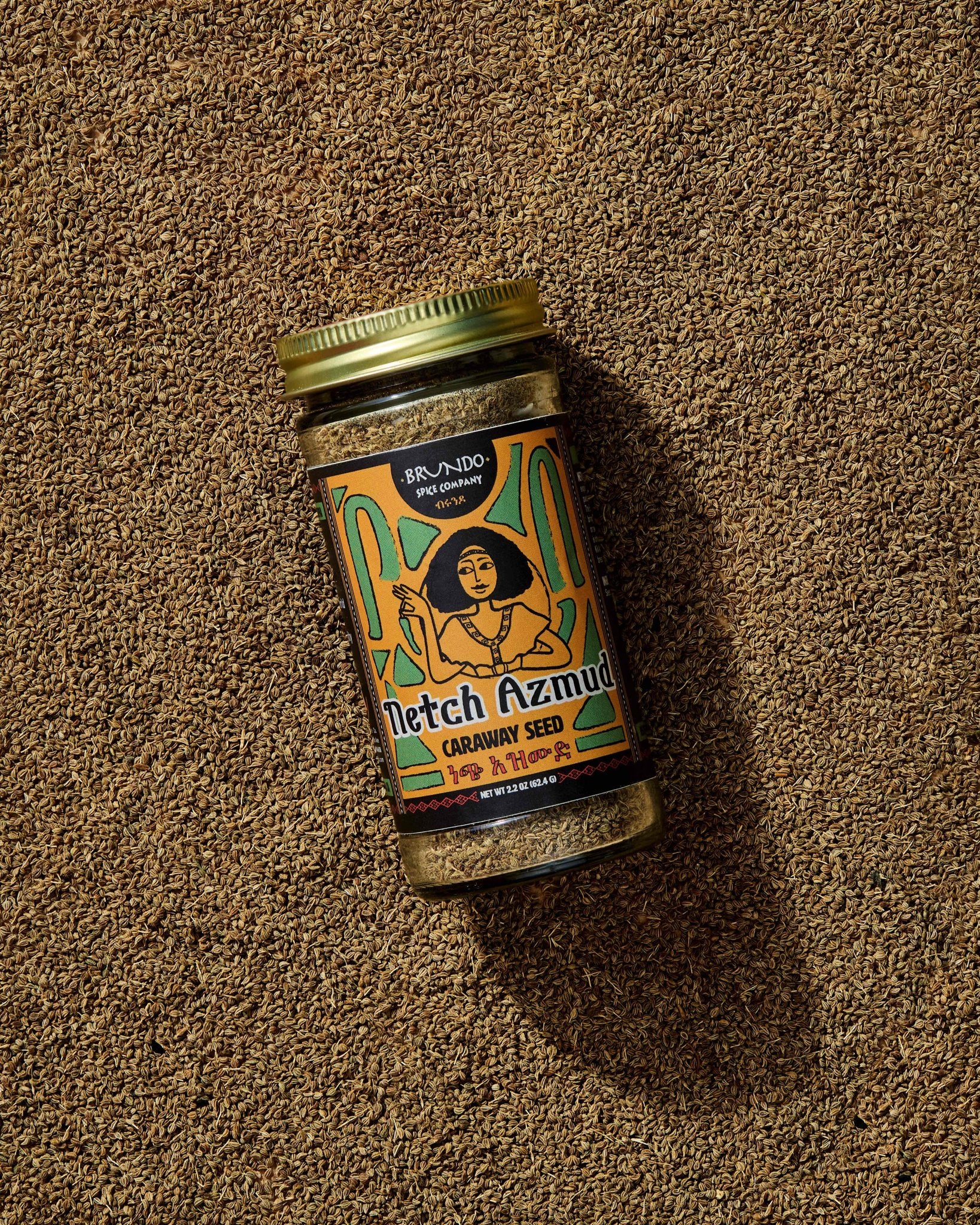 Brundo Spice Company Netch Azmud Ethiopian Caraway Seed jar resting on a bed of whole caraway seeds.