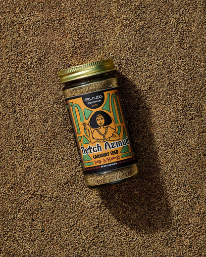 Brundo Spice Company Netch Azmud Ethiopian Caraway Seed jar resting on a bed of whole caraway seeds.